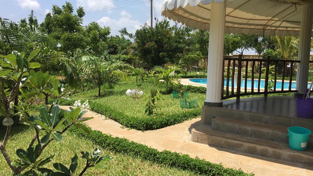 Asili Yetu — landscaped garden pathway leading to gazebo and pool