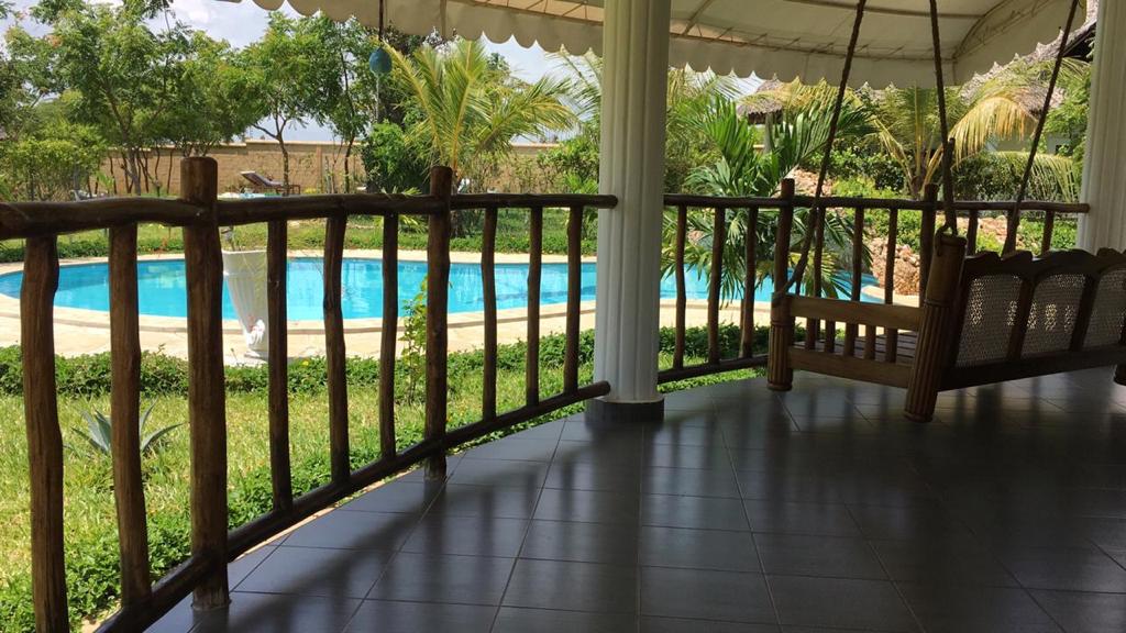 Asili Yetu — pool view from villa veranda framed by timber railings