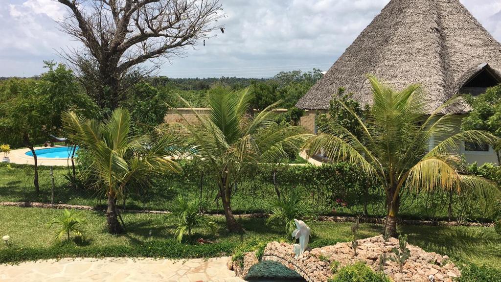Asili Yetu — elevated view of thatched villa, pool, and palm-filled gardens