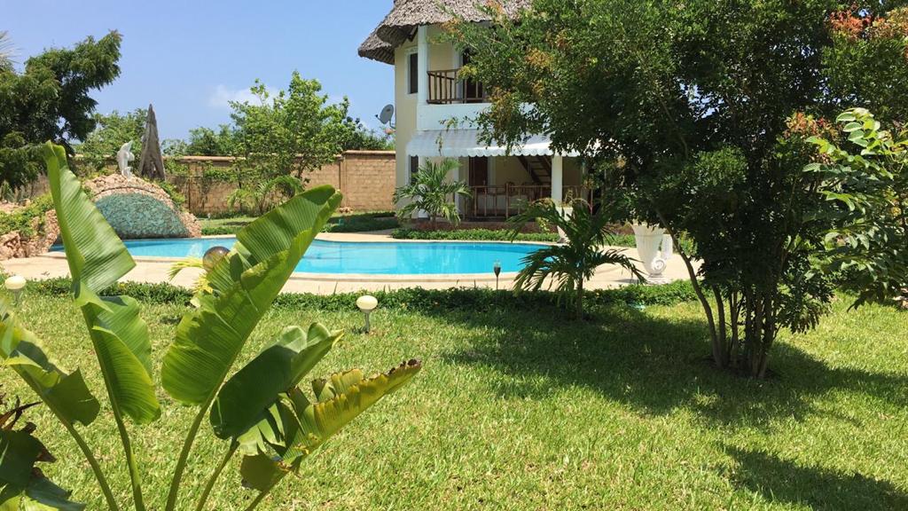 Asili Yetu — villa with thatched roof and pool surrounded by tropical gardens